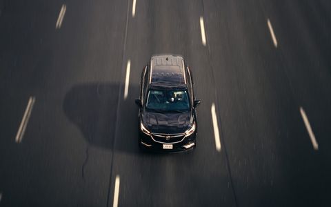 Aerial view of a black car driving on a multi-lane highway