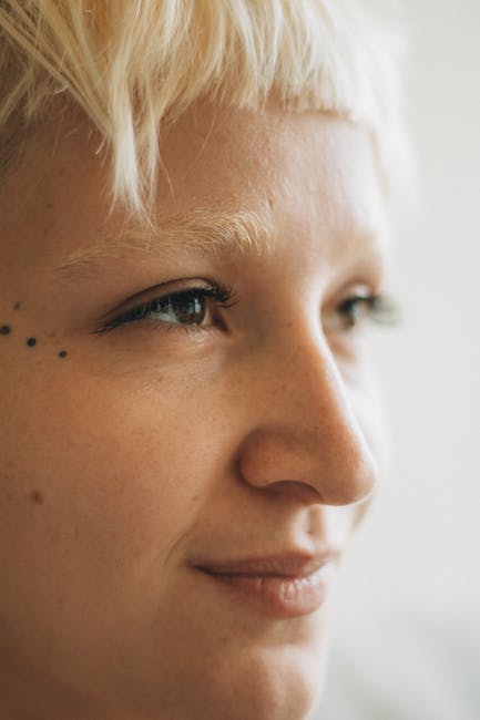 Detailed close-up of a person with facial piercings and short blonde hair.