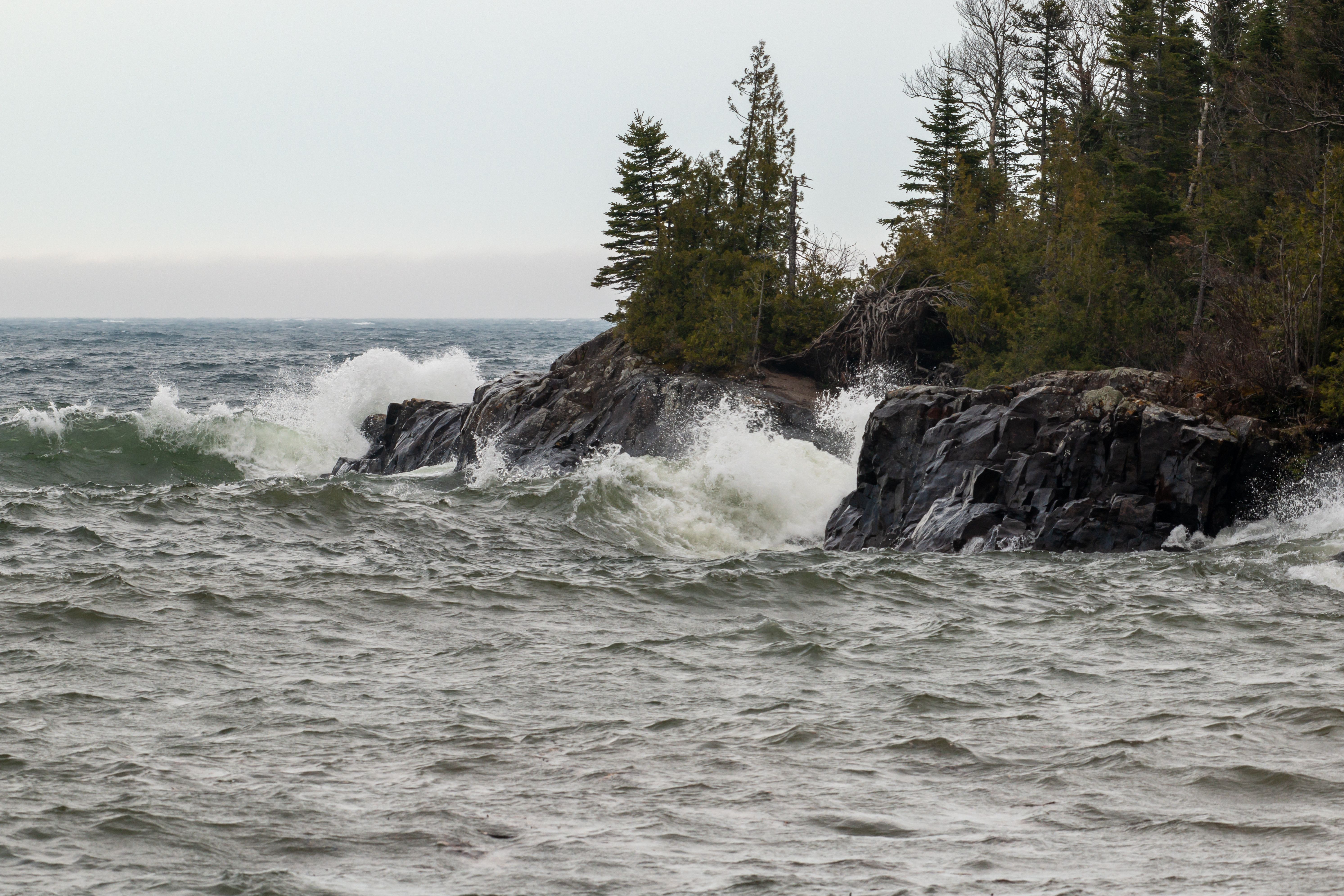 Dramatic scene of waves crashing against rocky Lake Superior shoreline.
