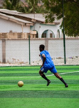 A young male soccer player in action on an outdoor field, poised to kick the ball during a match.