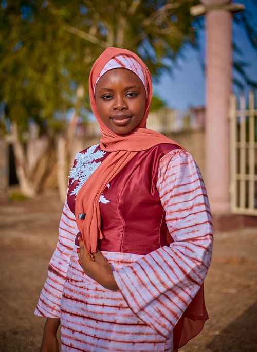Free A woman in a stylish hijab and colorful attire confidently posing outdoors on a sunny day. Stock Photo