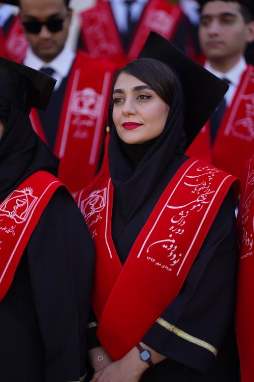 Free Iranian students in red sashes at a graduation ceremony outdoors. Stock Photo
