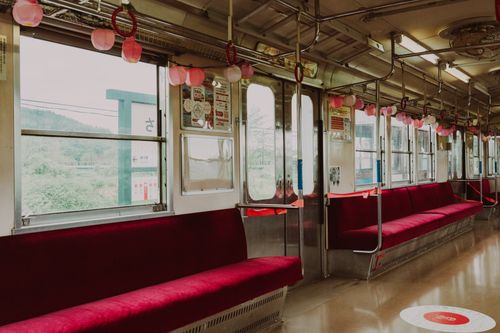 Free Interior view of an empty train carriage featuring red seats and decorative lanterns. Stock Photo