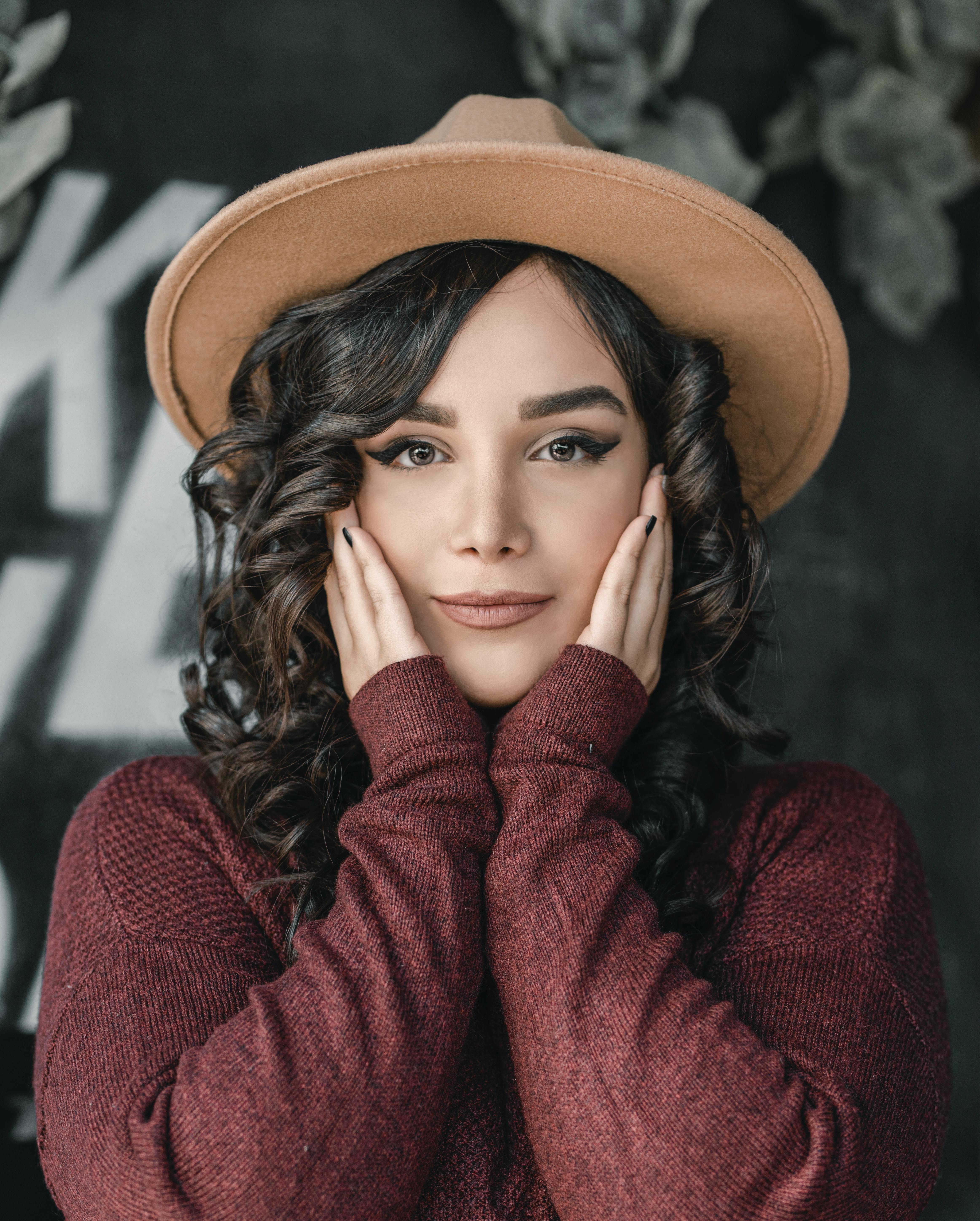 美女戴着帽子，穿着毛衣，双手捂脸，表情时尚优雅