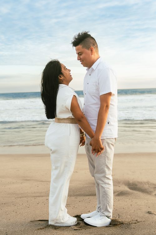 Free A loving couple holding hands and gazing at each other on a picturesque beach at sunset. Stock Photo