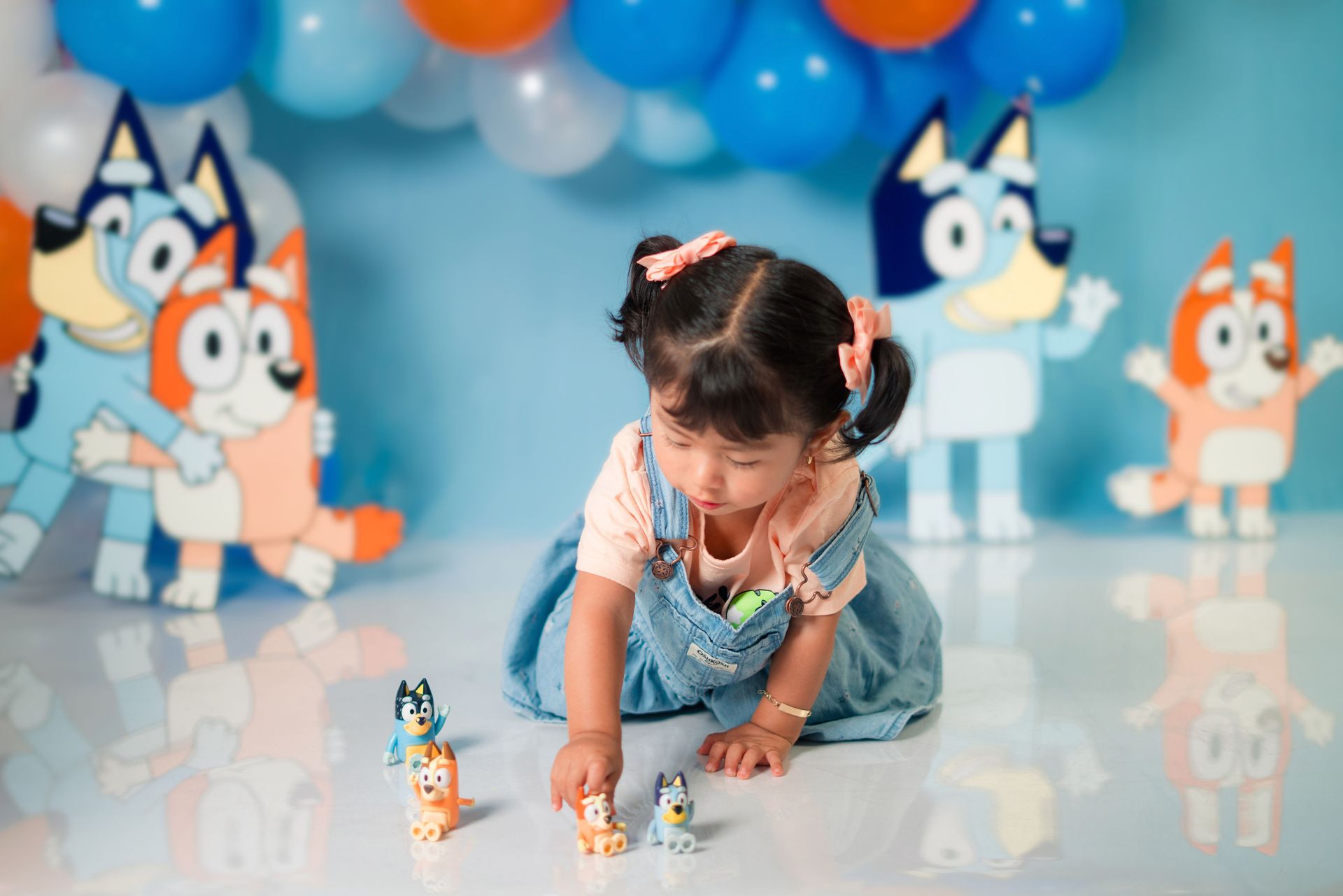 Young girl playing with toy figures at a vibrant, cartoon-themed birthday party