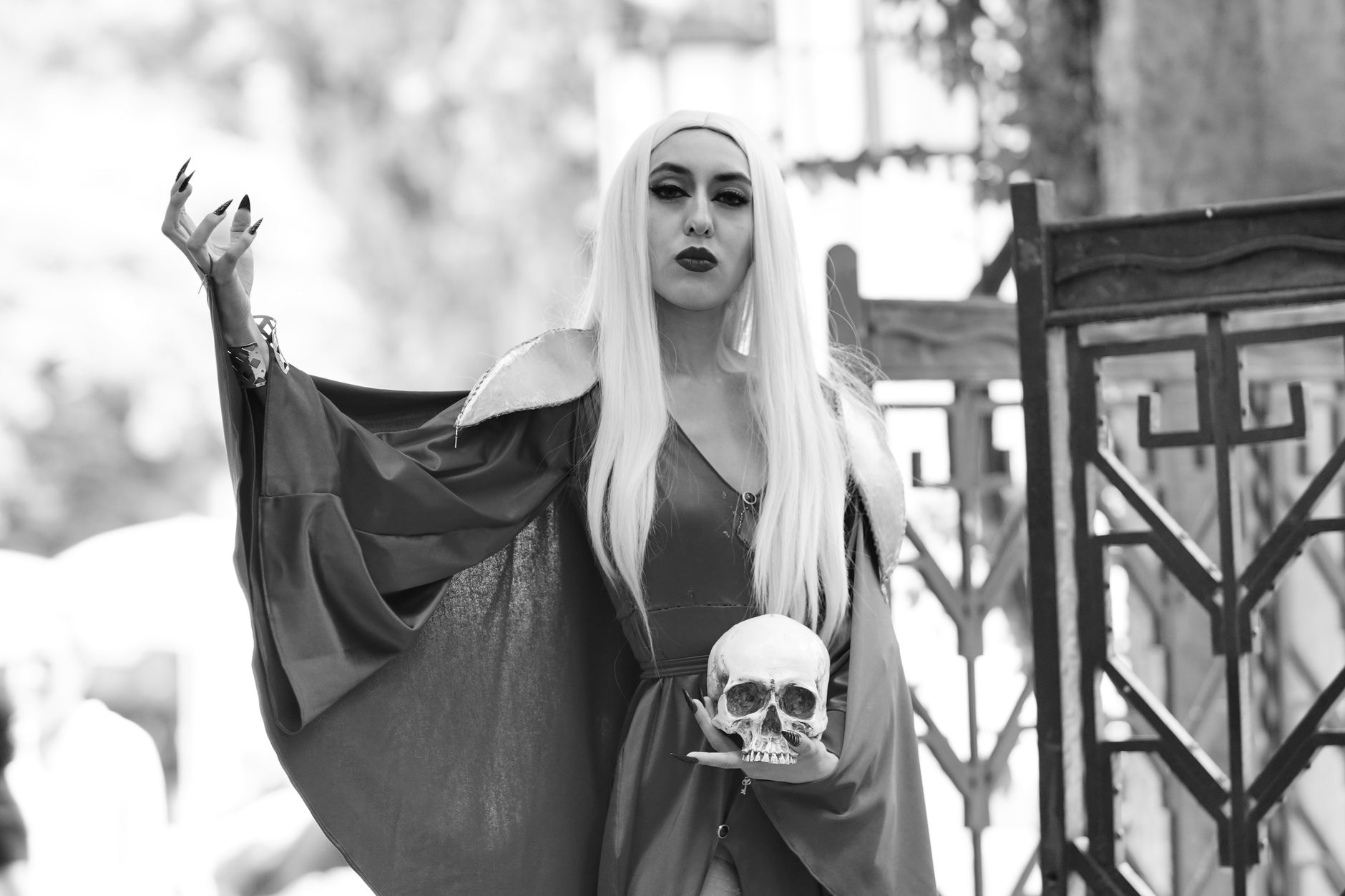 Mysterious gothic woman in dramatic costume holding a skull in a black and white setting.