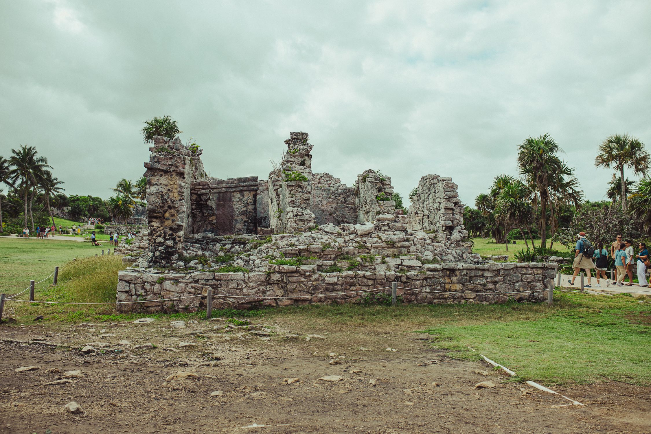 Explore the ancient Mayan ruins in Tulum, Mexico, set against lush greenery and a cloudy sky.