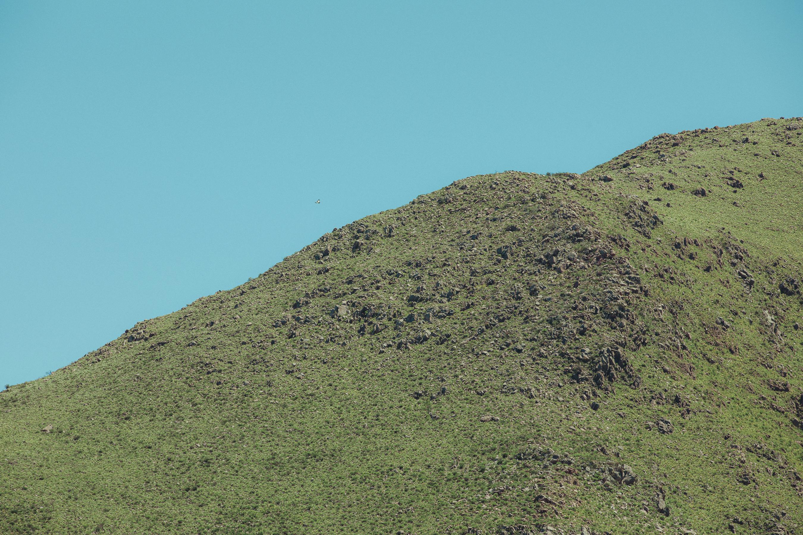 Gratis Smukke grønne bakker med minimal klippefremspring under en klar blå himmel, fanget i Córdoba, Argentina. Lagerfoto