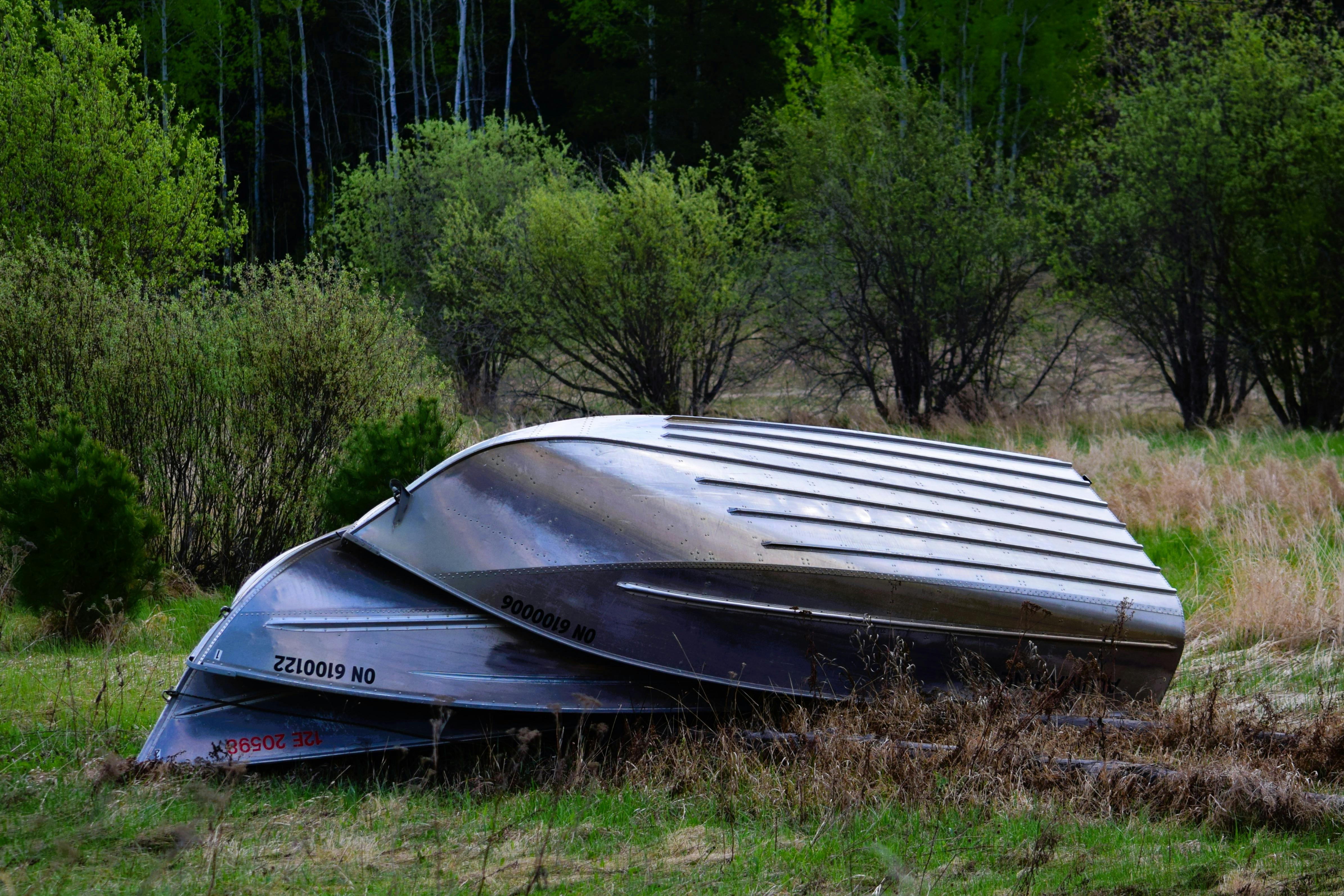 Upside down boats in a lush landscape in Dinorwic, Ontario, Canada surrounded by spring foliage.