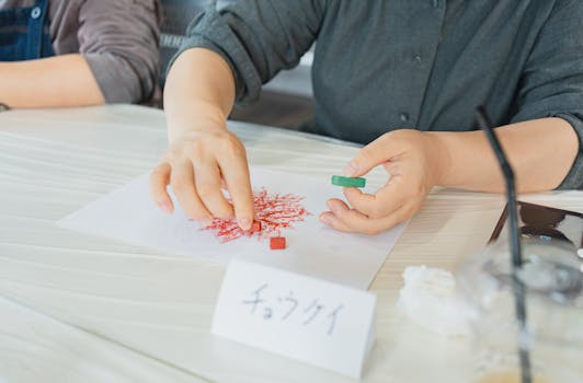 Hands creating pastel artwork during an art class in Shinjuku, Tokyo, Japan.