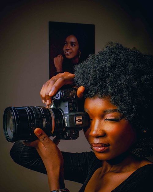 Free Young female photographer using a camera with a portrait in the background. Stock Photo