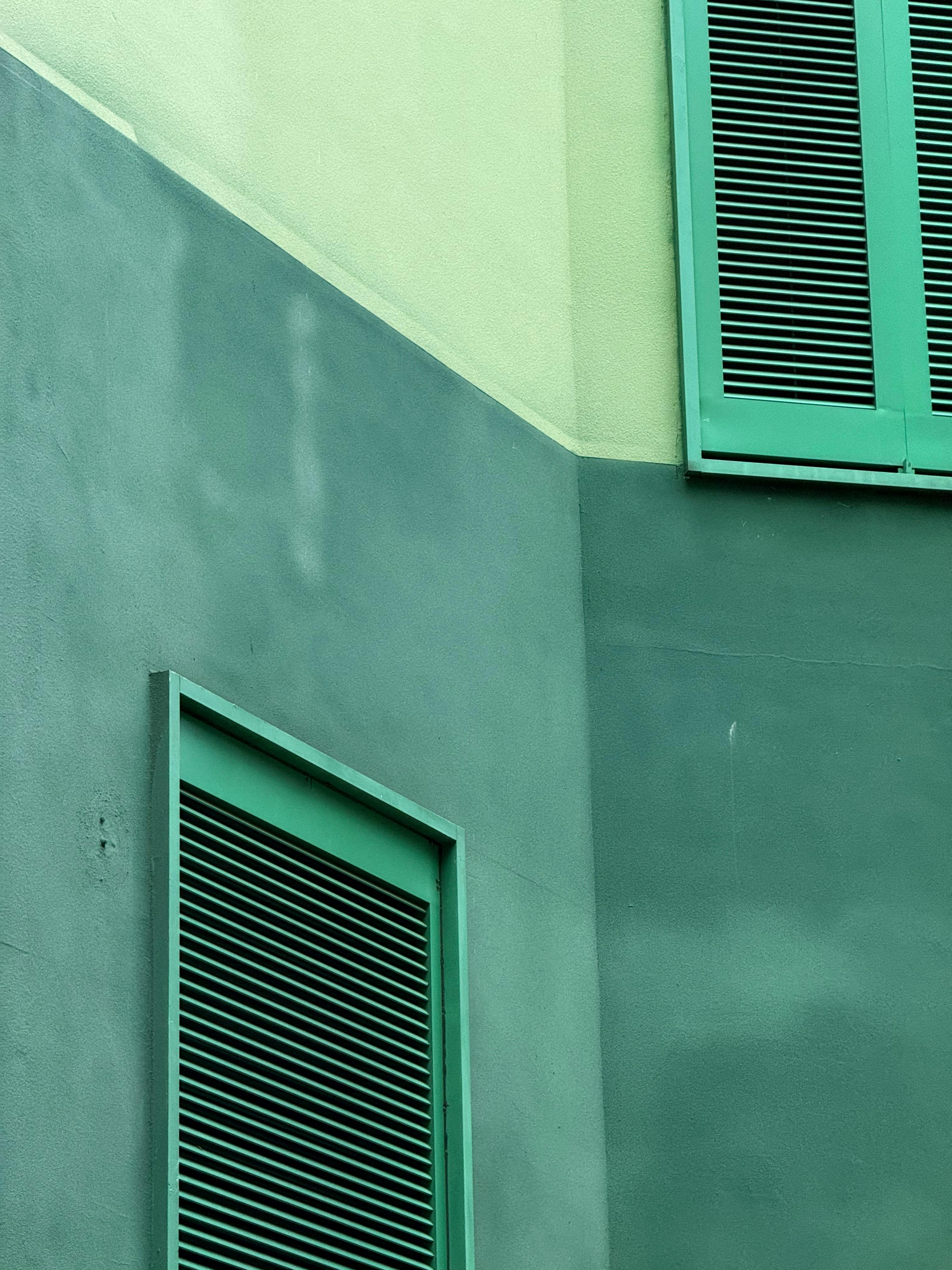 bezplatná Abstraktní pohled na moderní fasádu budovy se zelenými panely, které zdůrazňují čisté linie a tlumené tóny. Základová fotografie