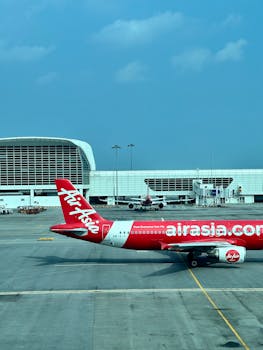 AirAsia aircraft taxiing at a modern airport, showcasing vibrant travel vibes.