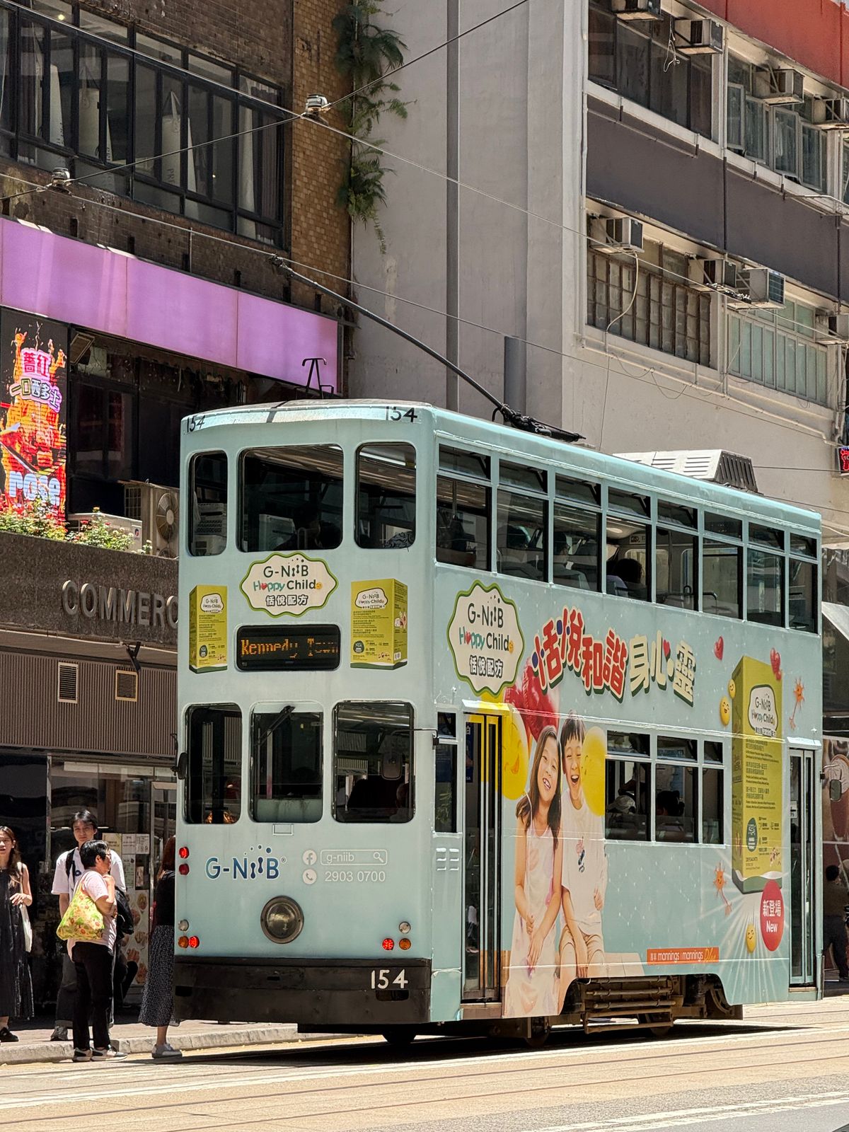 Vintage double-decker tram passing through a busy Hong Kong street