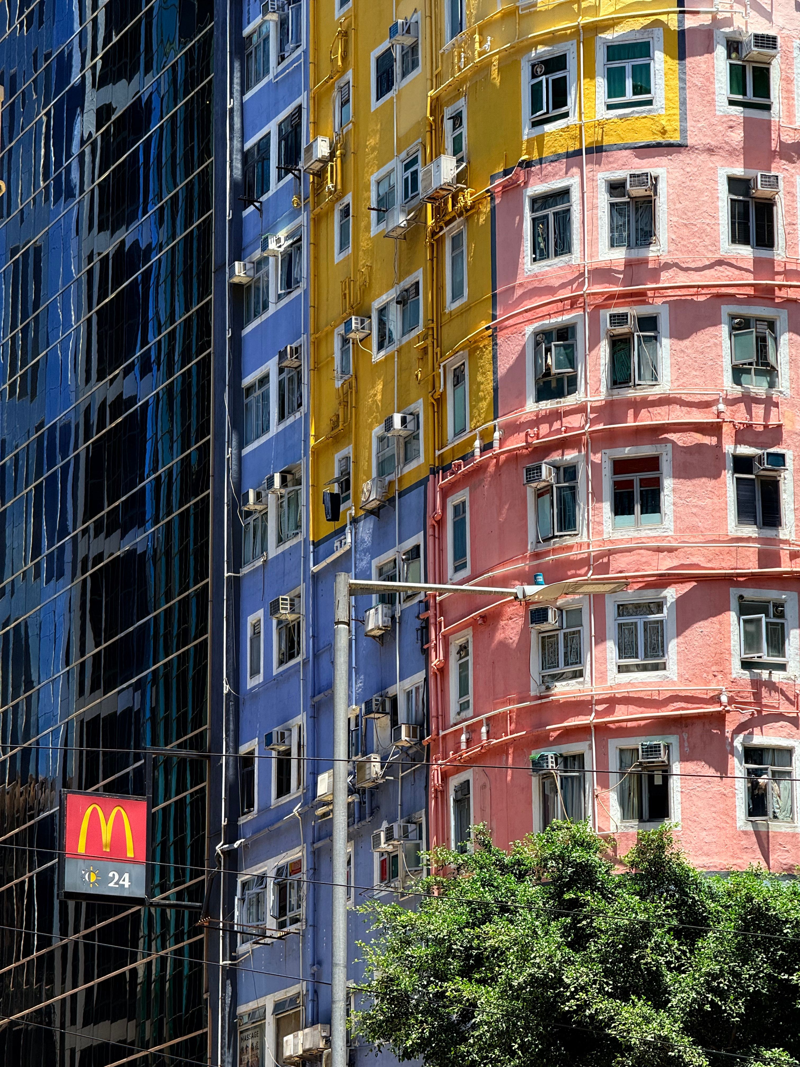 Vibrant blue, yellow, and pink buildings with McDonald's logo under sunny sky.