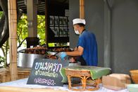 Street vendor preparing traditional Thai coconut pancakes at an outdoor market.