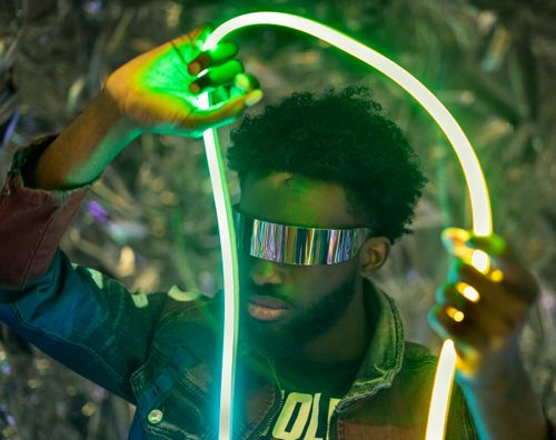Free Man with futuristic sunglasses holding neon lights, vibrant colors Stock Photo