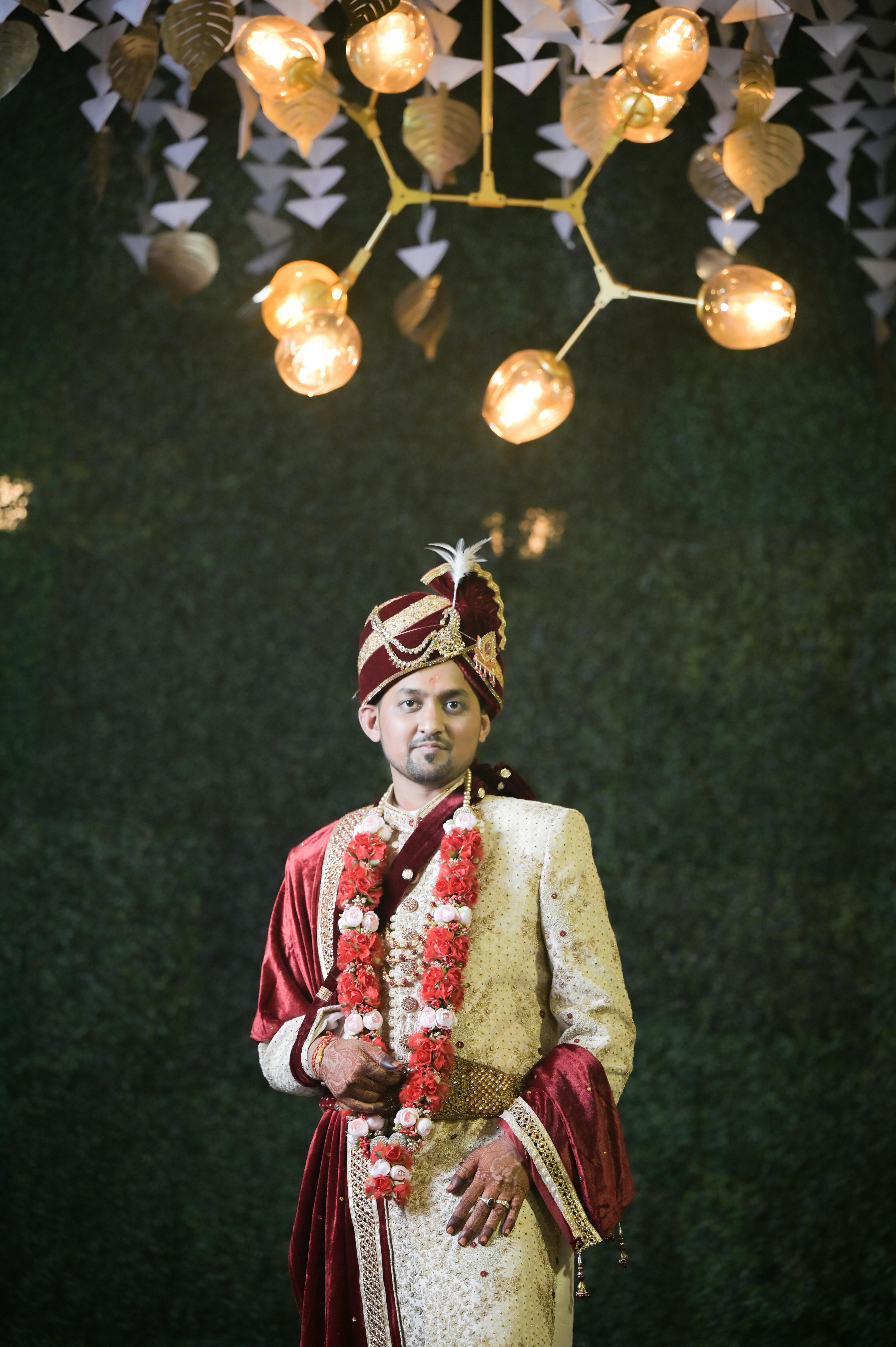 Free Portrait of a groom in traditional South Asian wedding attire under decorative lighting. Stock Photo
