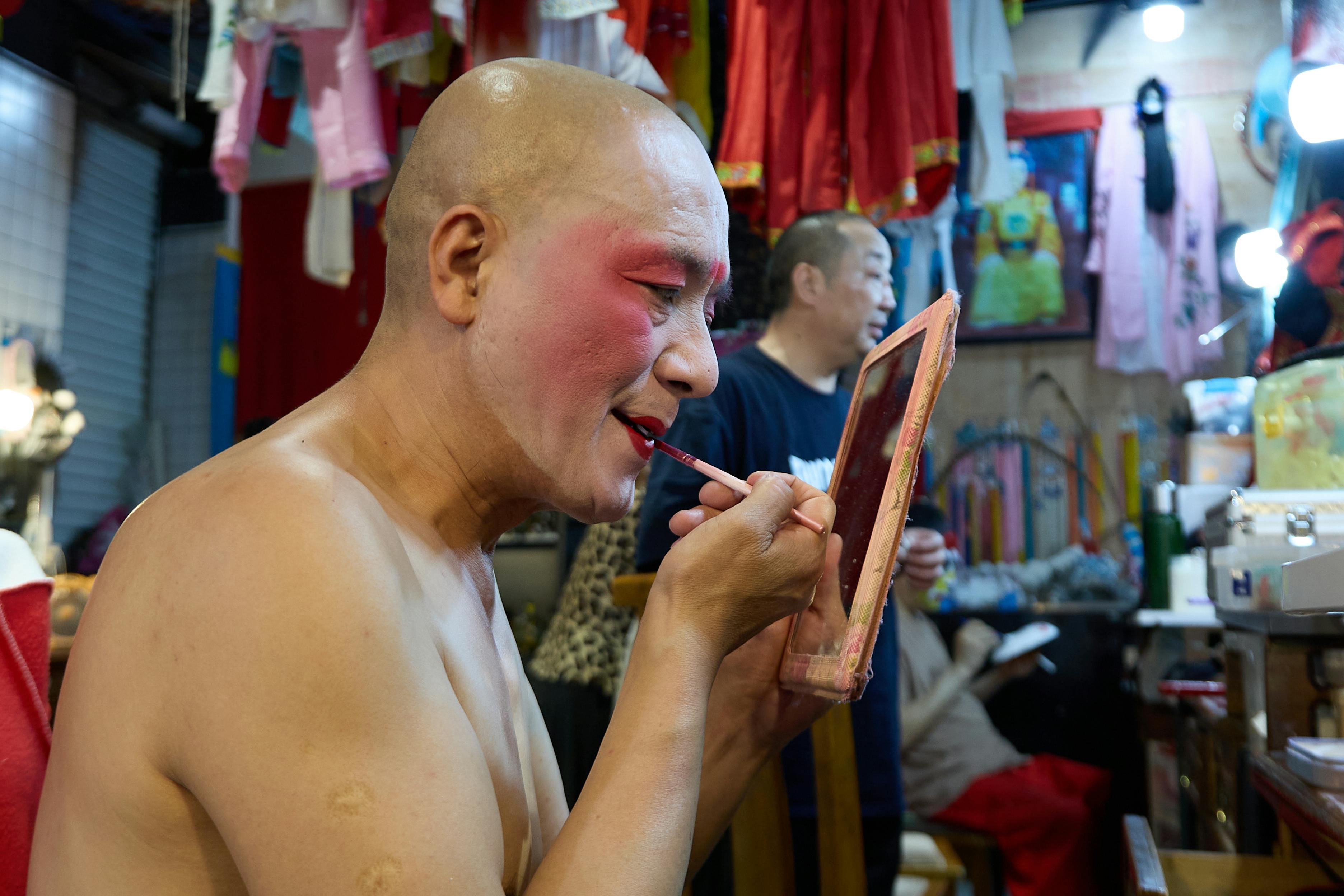 Free A traditional stage actor carefully applies makeup backstage, preparing for a performance. Stock Photo