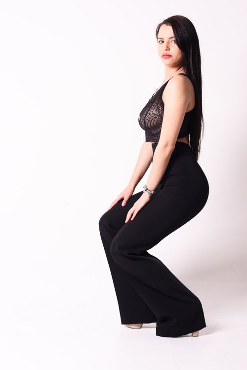 Free Stylish woman posing in a black lace top and pants against a white background. Stock Photo