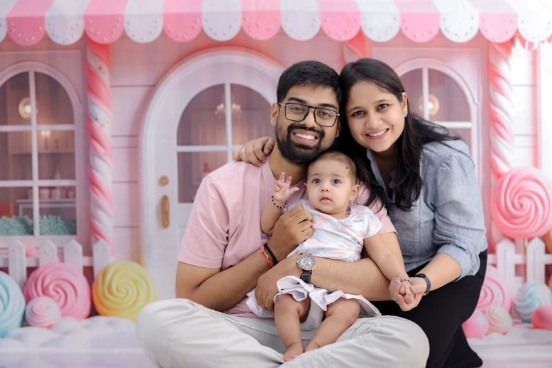 Happy family sitting in front of a colorful candy-themed backdrop.