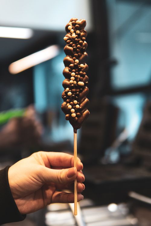 Free A close-up of a chocolate skewer with white pearls held by hand, set indoors. Stock Photo
