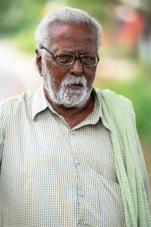 Free Portrait of an elderly man outdoors, wearing glasses and a casual shirt, with a thoughtful expression. Stock Photo