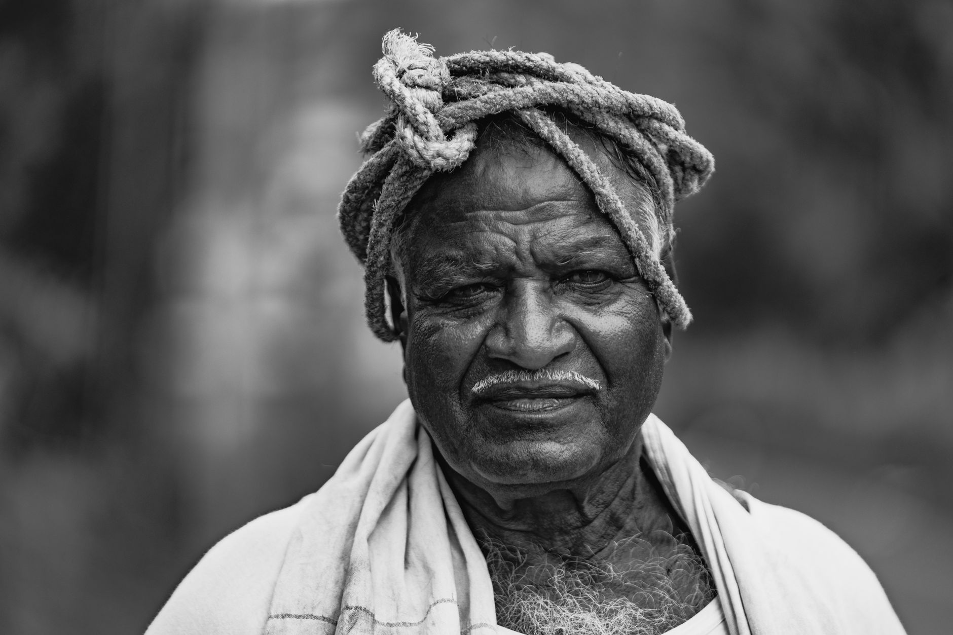 Black and white portrait of a senior man in traditional attire with a calm expression.