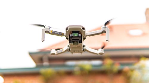 Free Close-up of a drone hovering outside with a blurred building in the background. Stock Photo