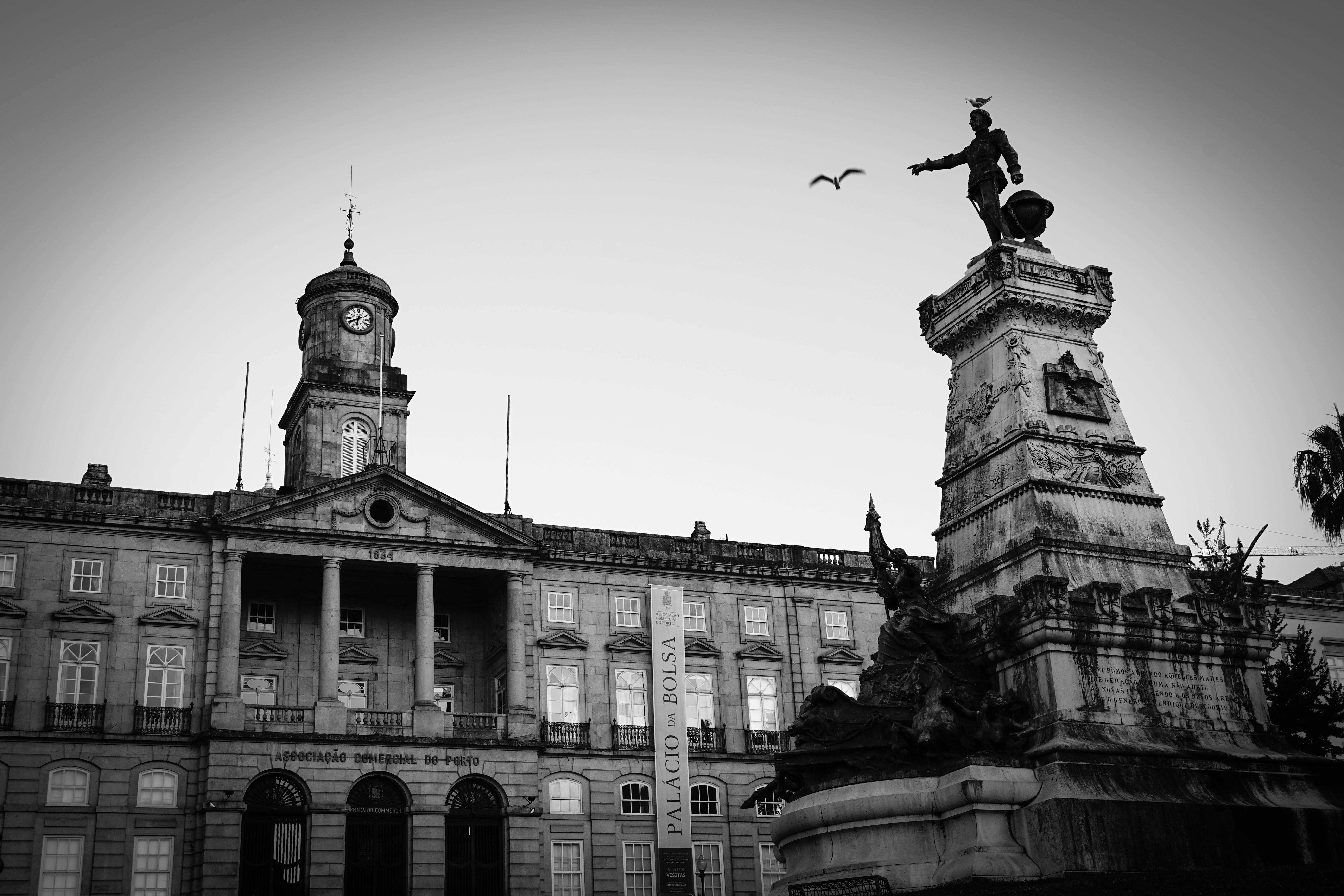 Black and white photo of historic architecture in Porto, featuring a statue and building.