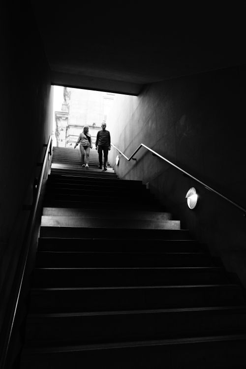 Free Black and white photo of a couple walking down stairs in a city environment. Stock Photo