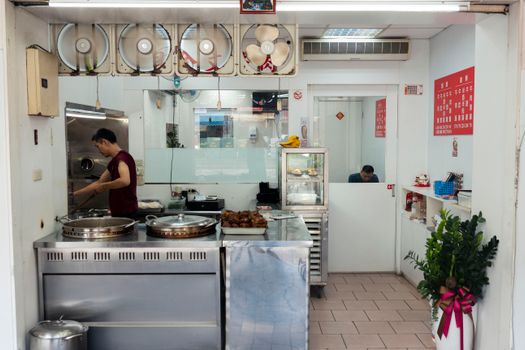 Chef cooking in an Asian restaurant kitchen with visible equipment and a clean setting.