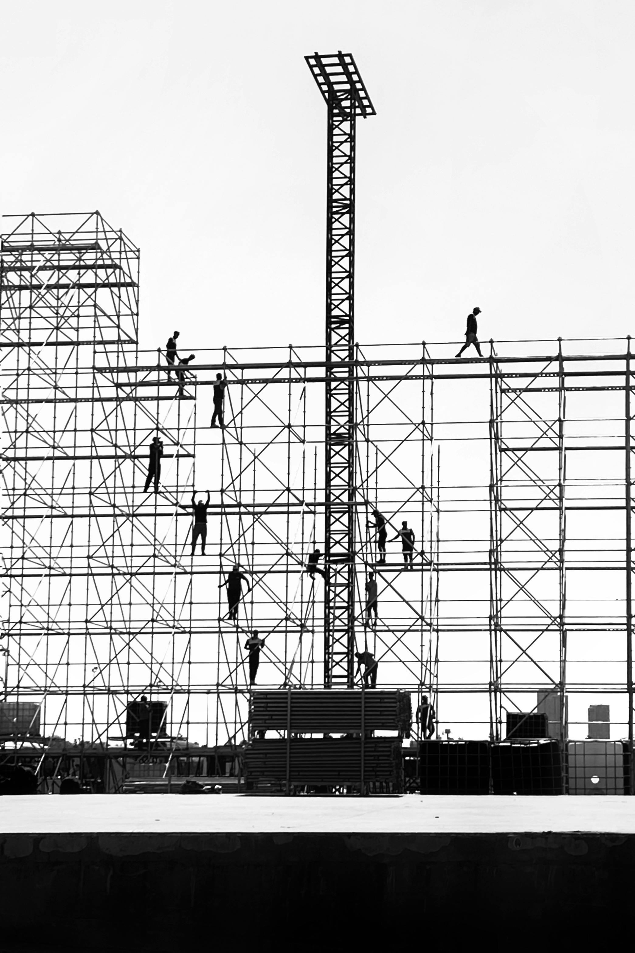 Silhouetted workers on scaffolding against the sky, depicting urban construction dynamics.