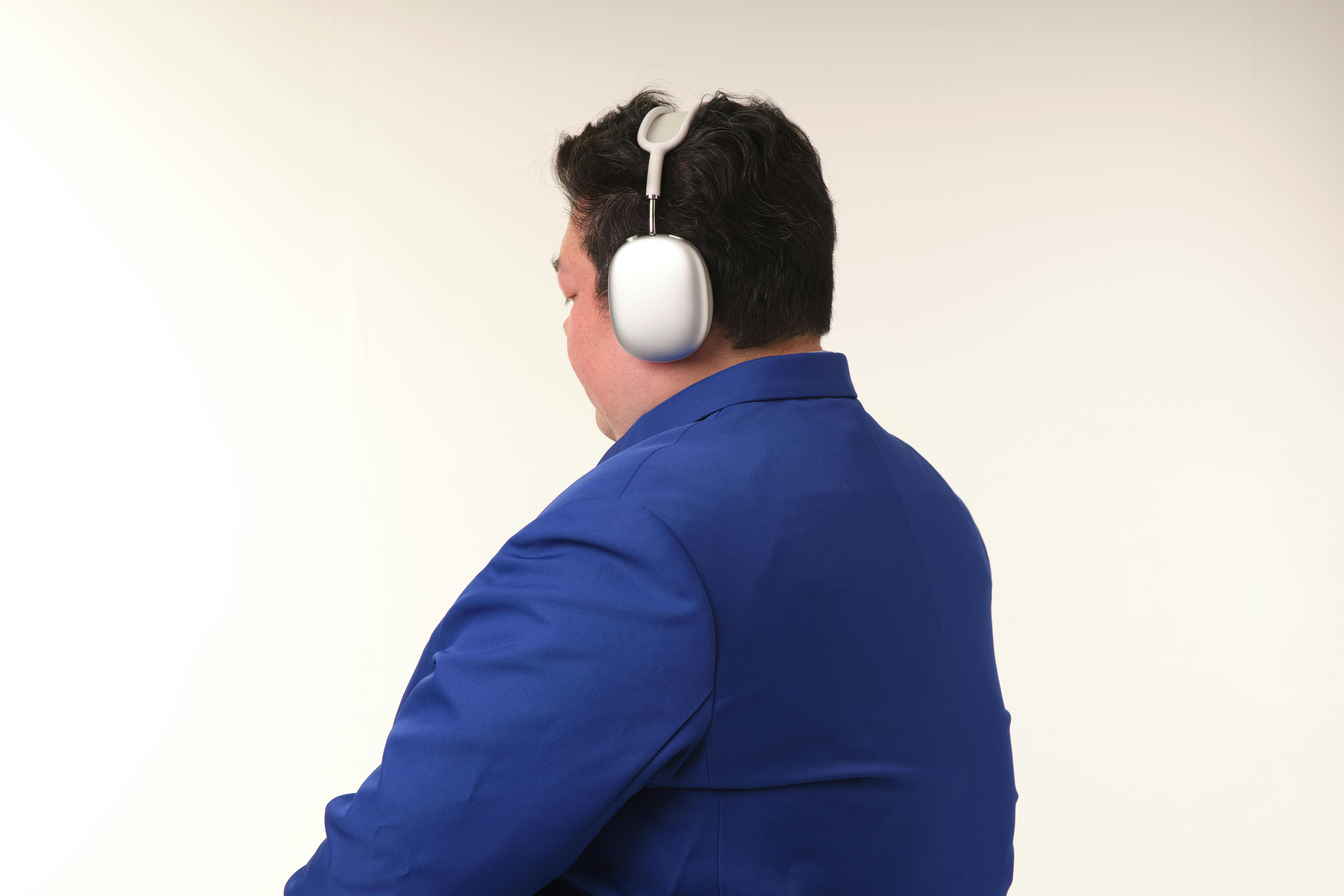 Gratis Tampak belakang orang berjas biru dan memakai headphone dalam suasana minimalis. Foto Stok