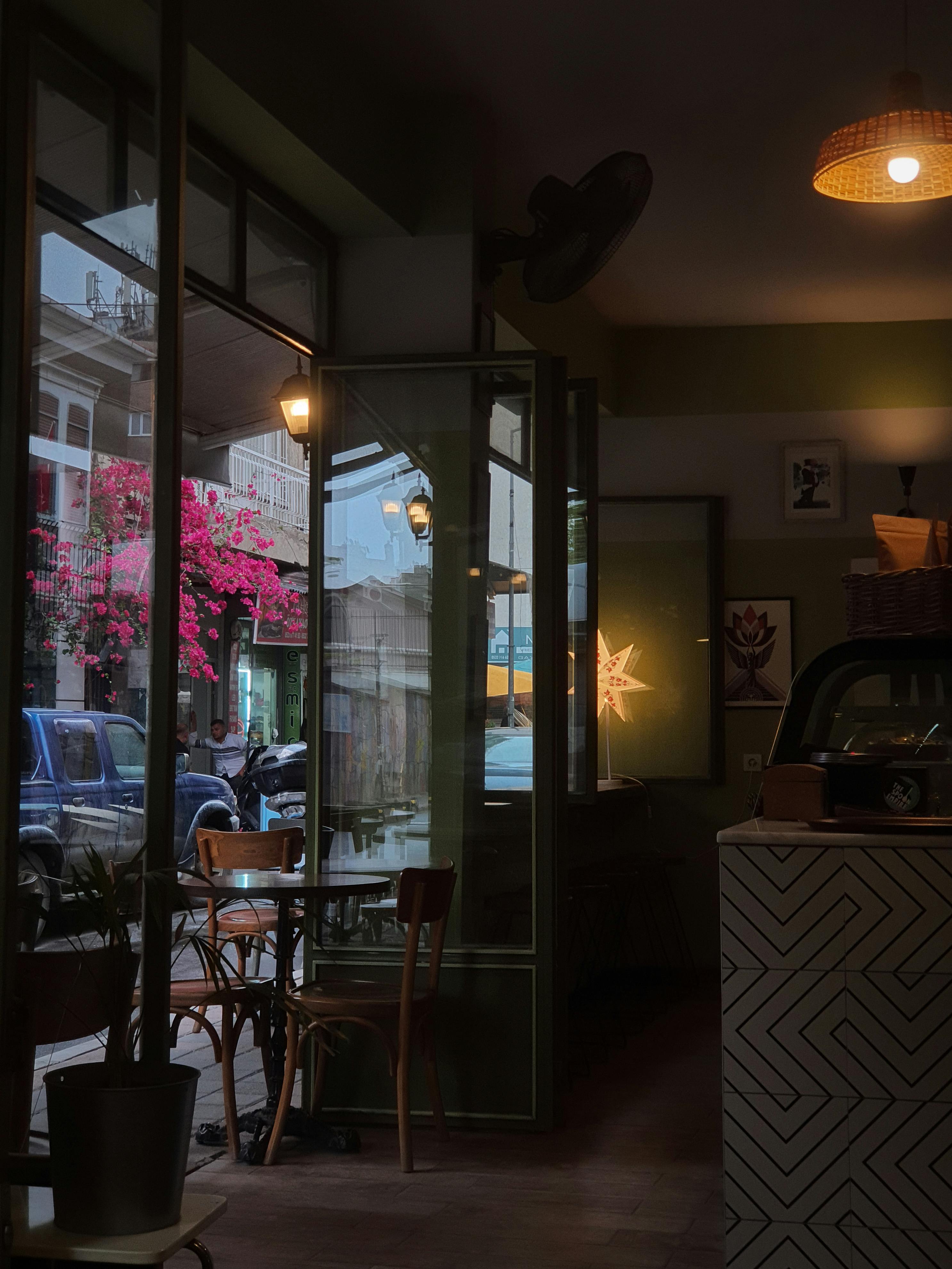 Warm cafe interior featuring floral street view through window, exuding cozy ambiance.