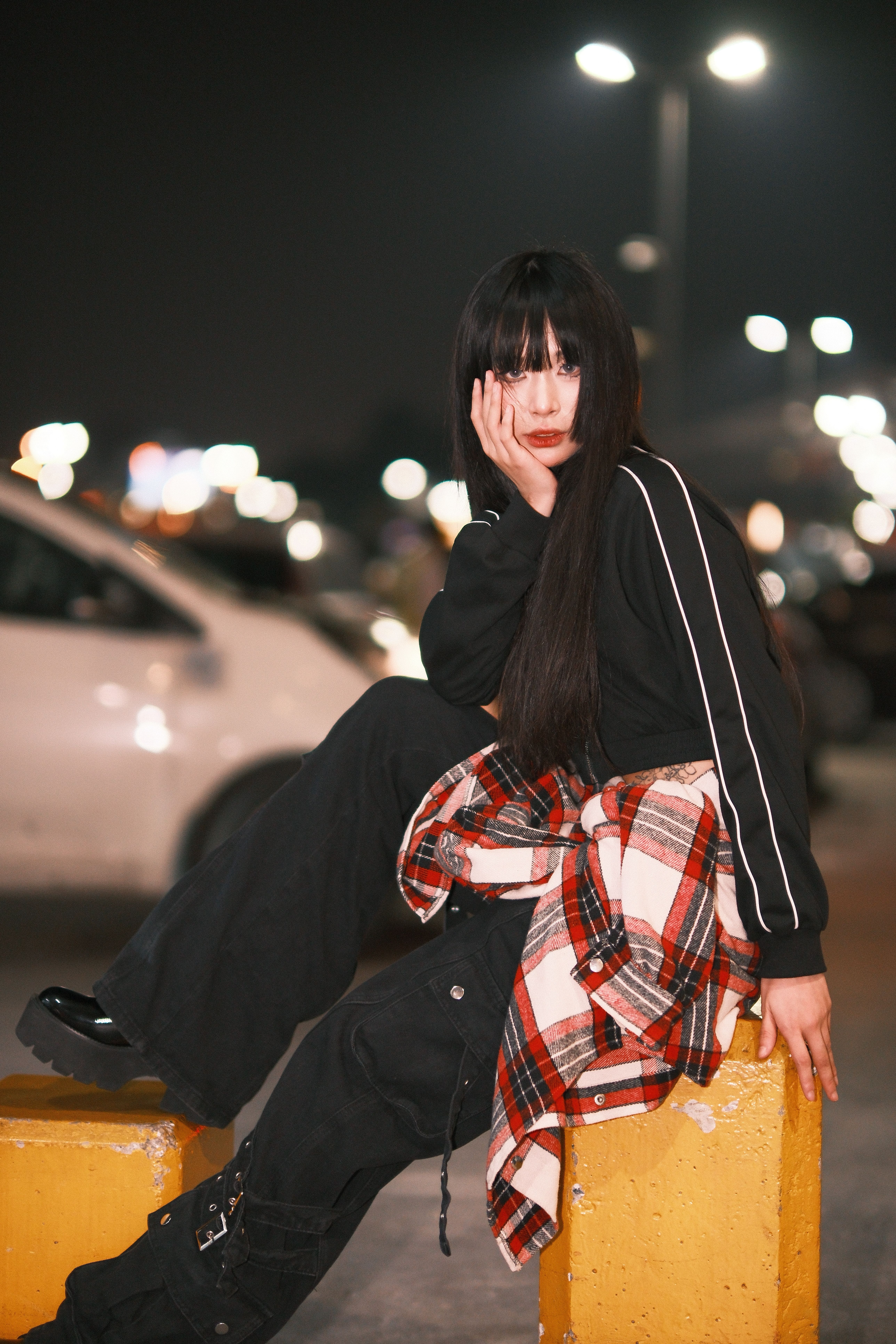 Fashionable young woman posing on city street at night, embracing urban style.
