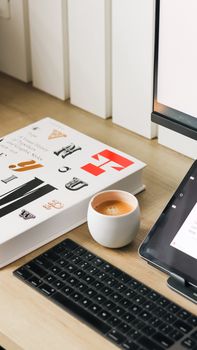 A sleek desk setup with tablet, keyboard, book, and coffee, perfect for productivity.