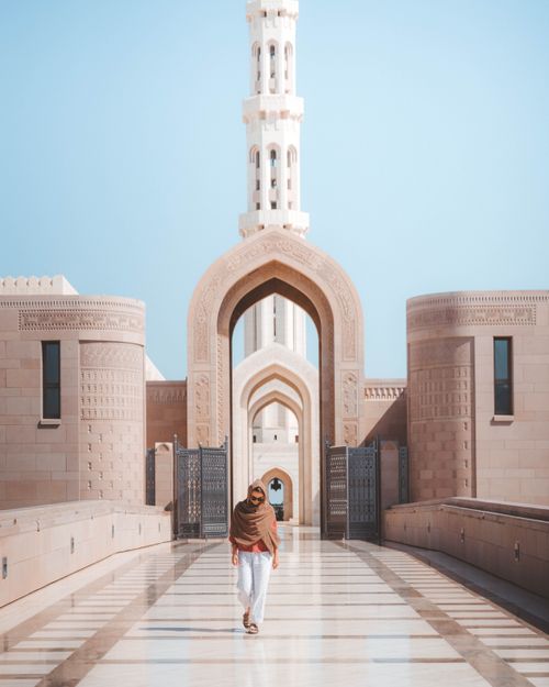 Free Person walking in front of a grand mosque showcasing beautiful modern Islamic architectural design. Stock Photo