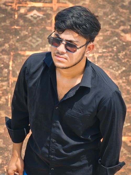 Free Portrait of a young adult man wearing sunglasses and black shirt, looking confident outdoors. Stock Photo