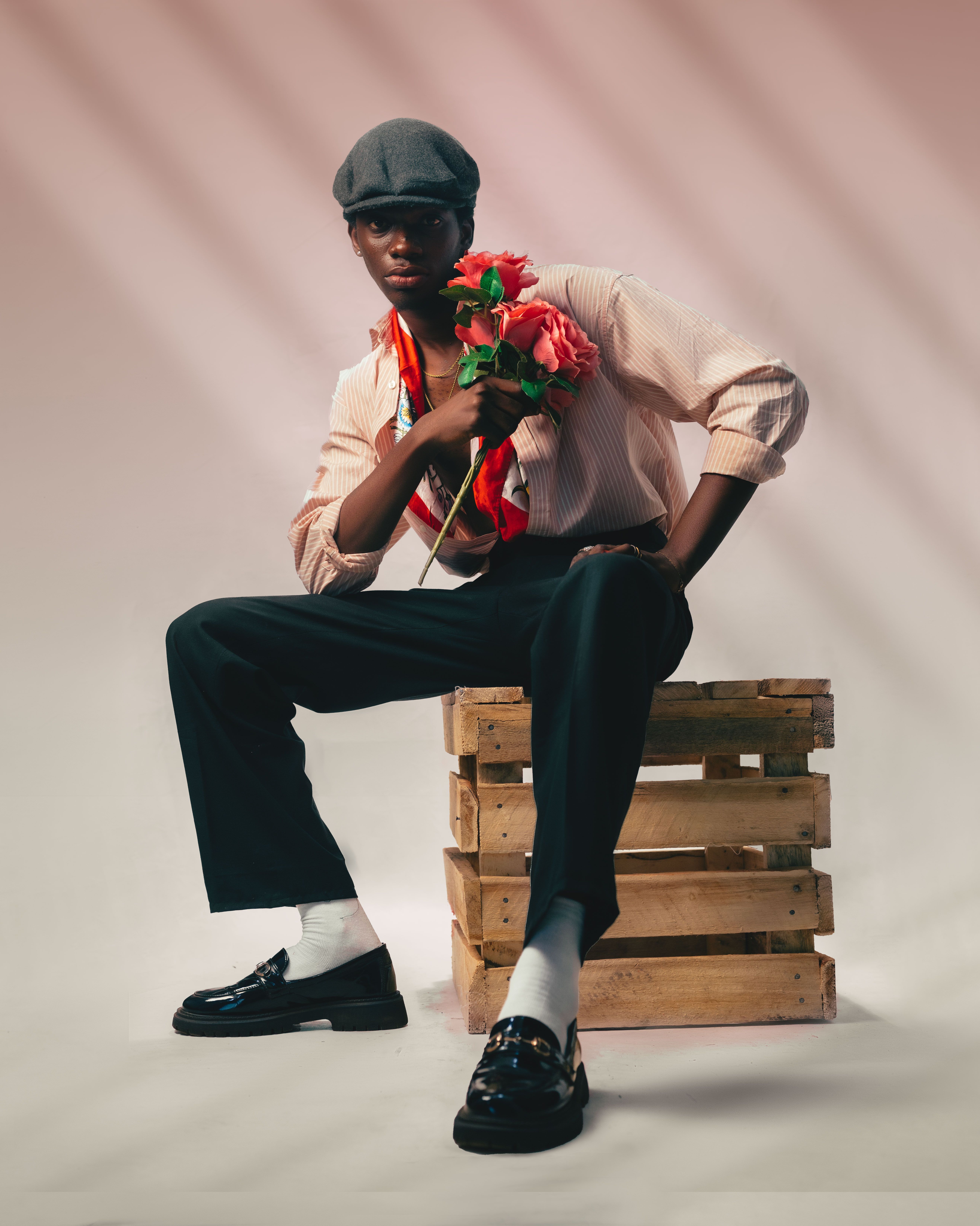 Black male model in vintage attire posing with roses on wooden crate