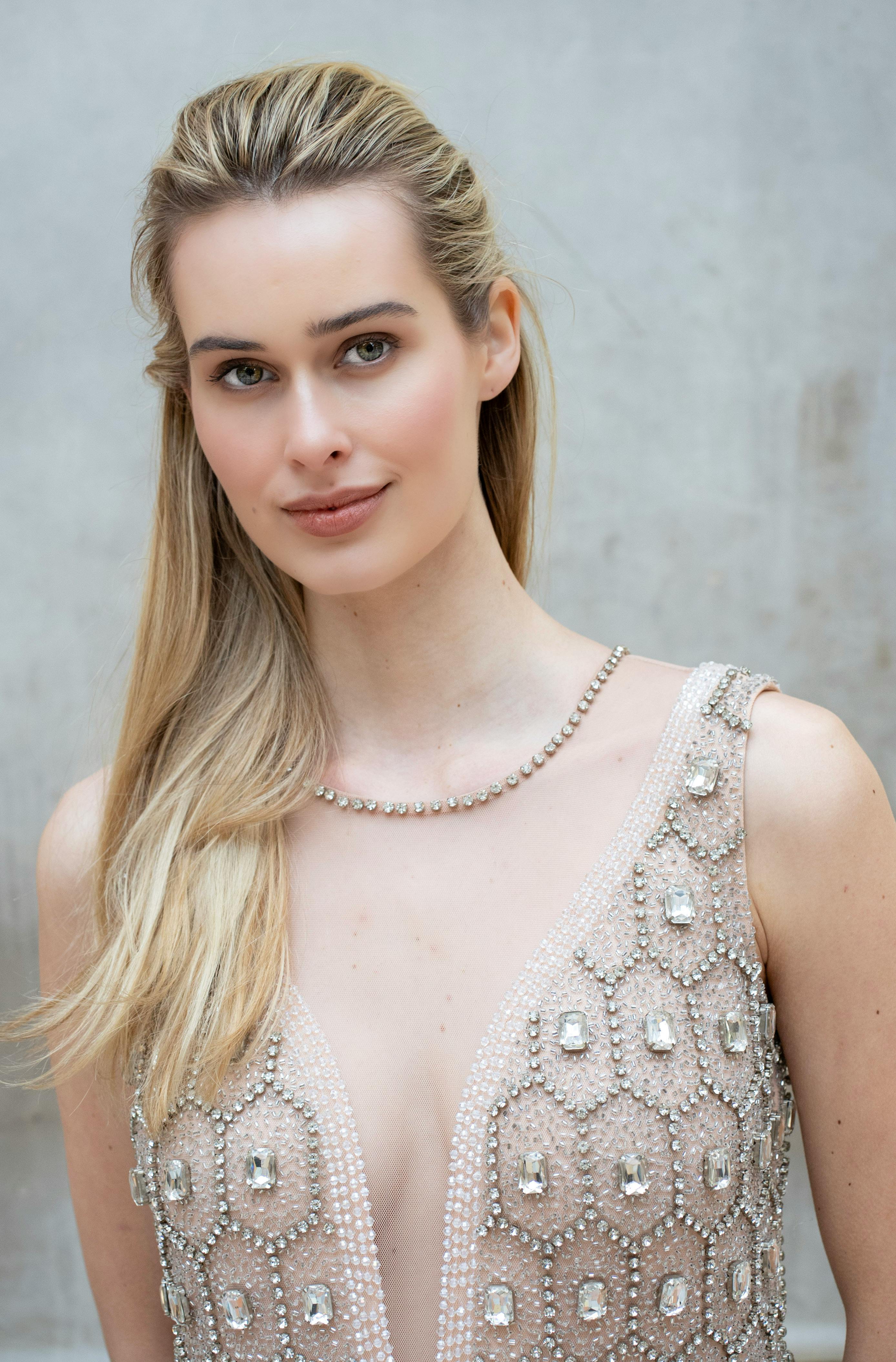 A beautiful young woman in a beaded dress posing confidently in Milan.