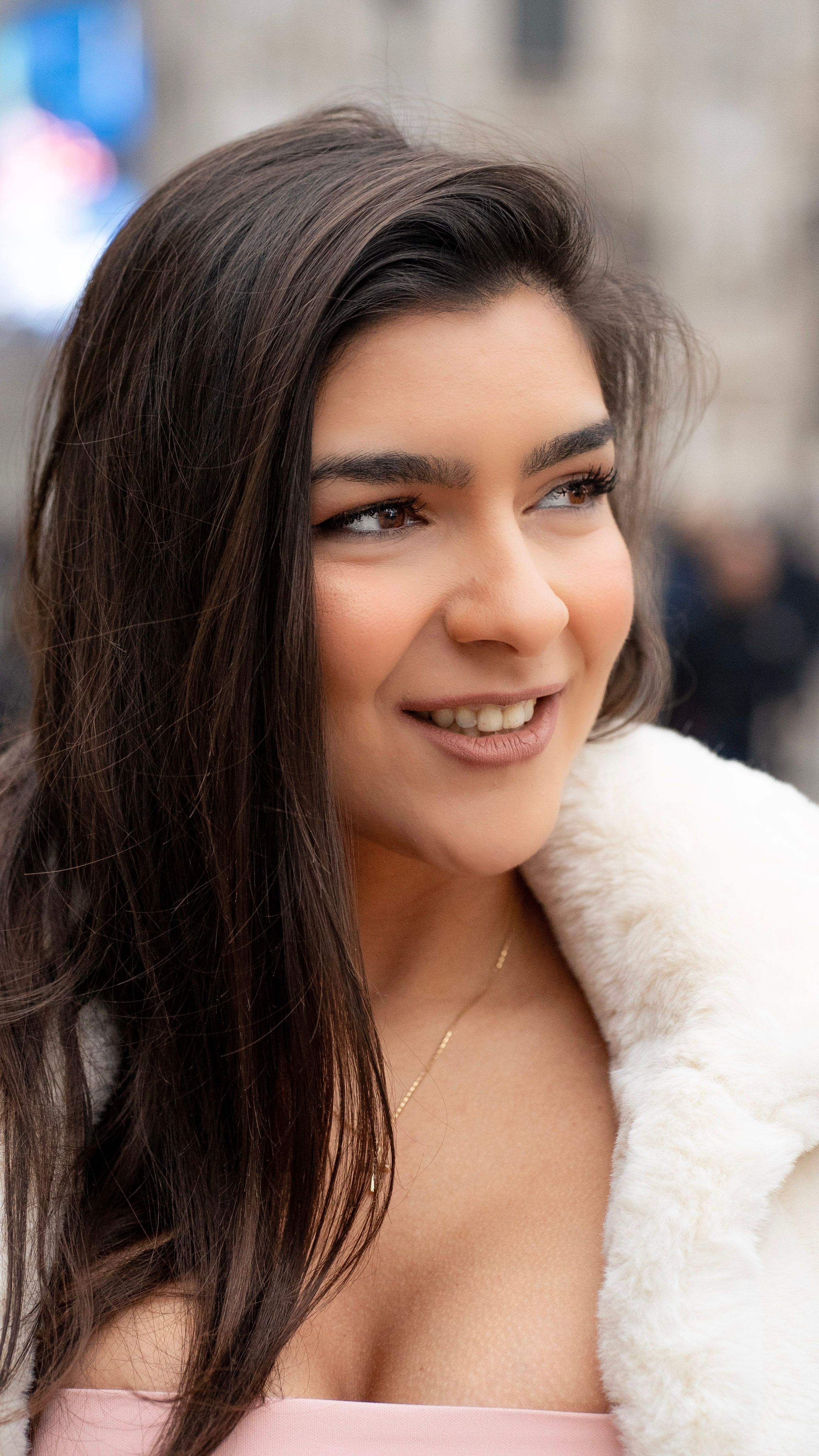 Elegant young woman posing outdoors in Milan, showcasing natural beauty and fashion style.
