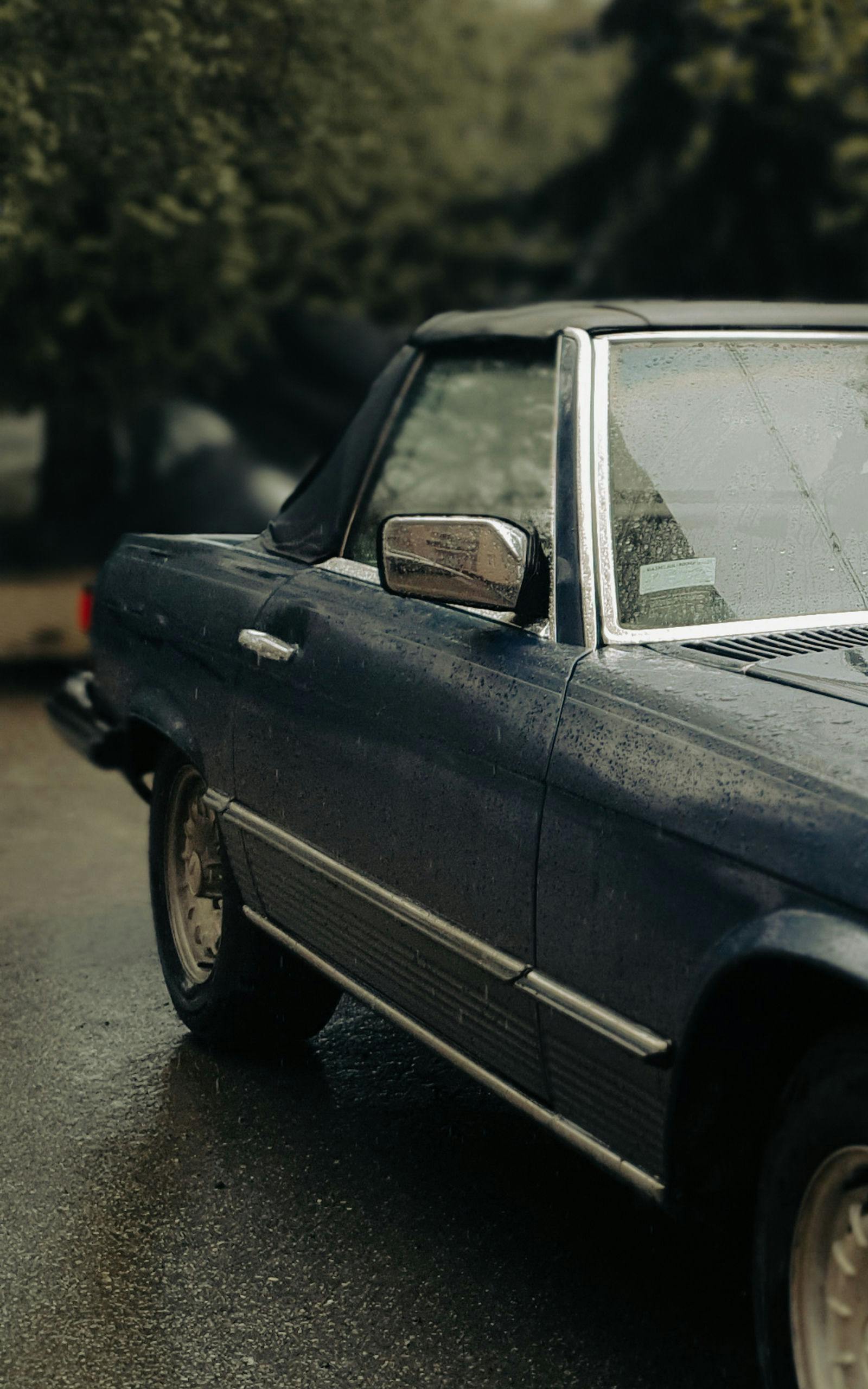 Classic vintage car parked outdoors in rain, capturing rainy day mood.