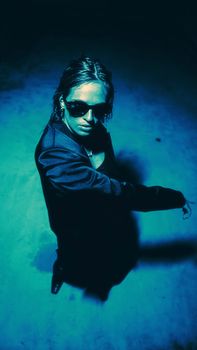 Dramatic portrait of a woman wearing sunglasses. Captivates with a blue, dark ambiance.
