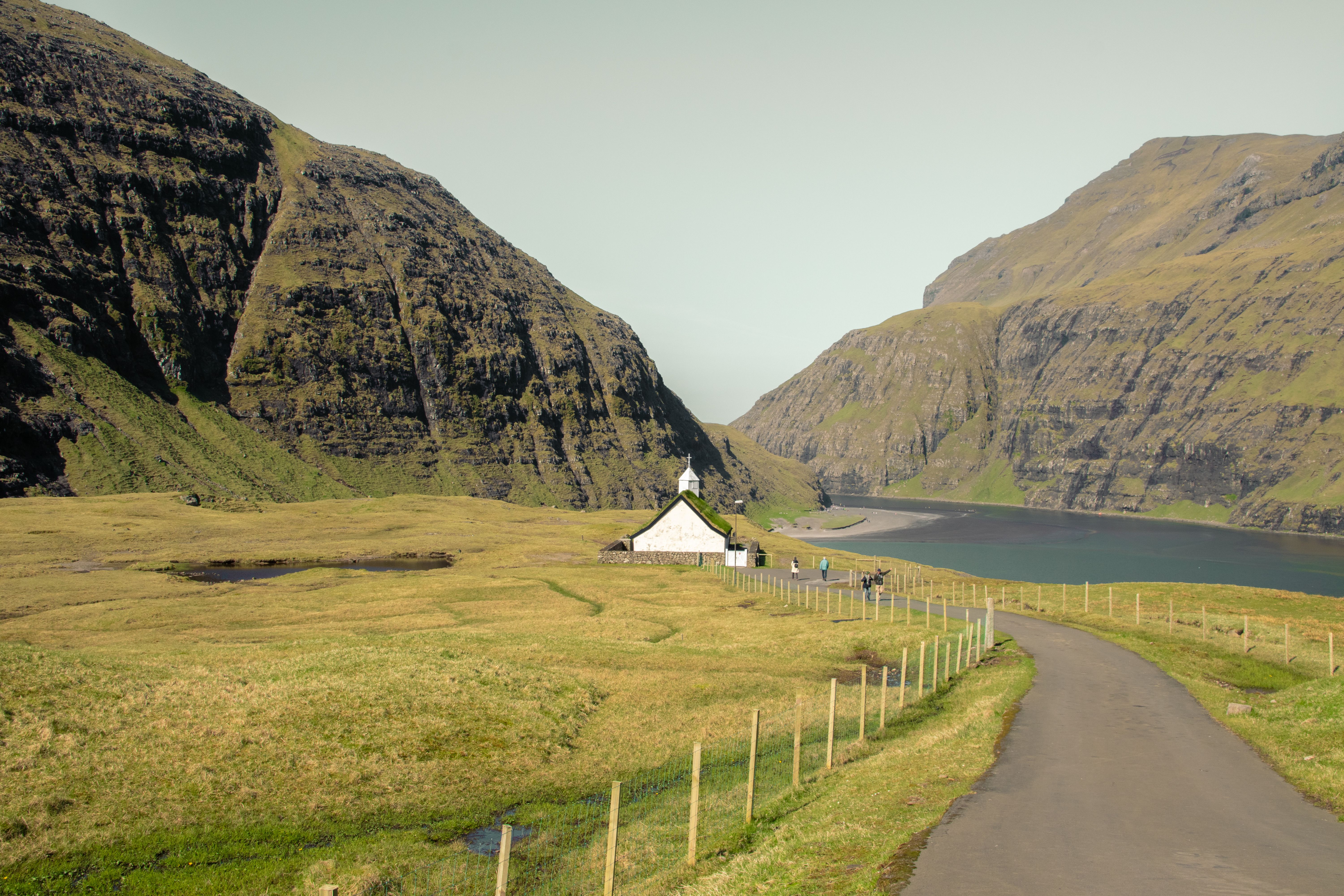 Explore the breathtaking scenery of Faroe Islands with cliffs, sea, and a quaint church.
