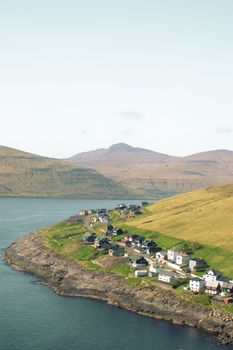 Stunning aerial view of a coastal village on the Faroe Islands surrounded by dramatic cliffs and ocean.