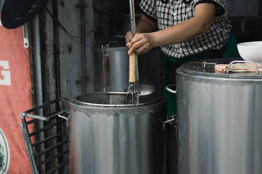 Street vendor preparing traditional Vietnamese noodles in Hanoi with stainless steel pots.