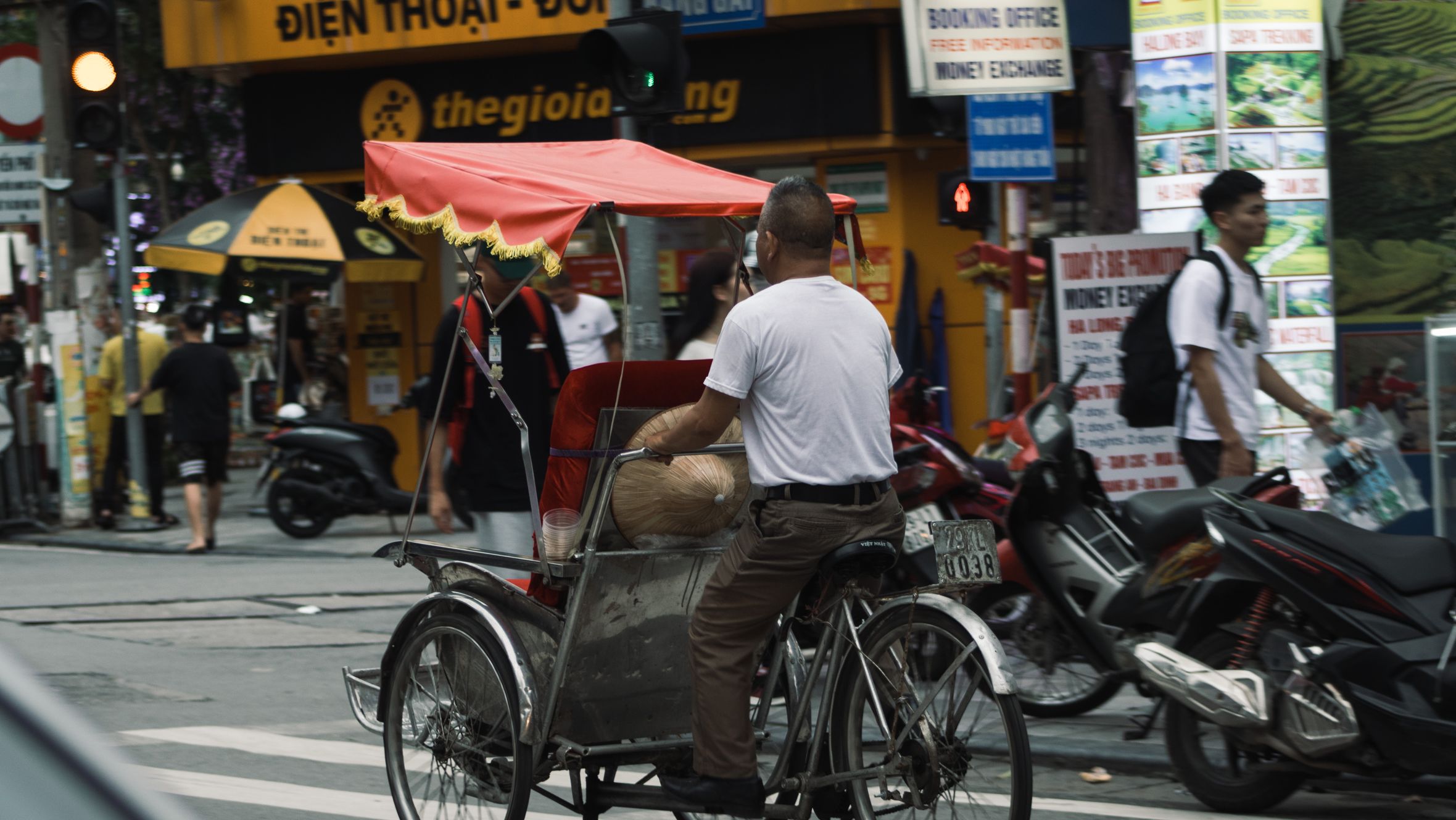 A vibrant street scene in Hanoi featuring a traditional cyclo and bustling street life.