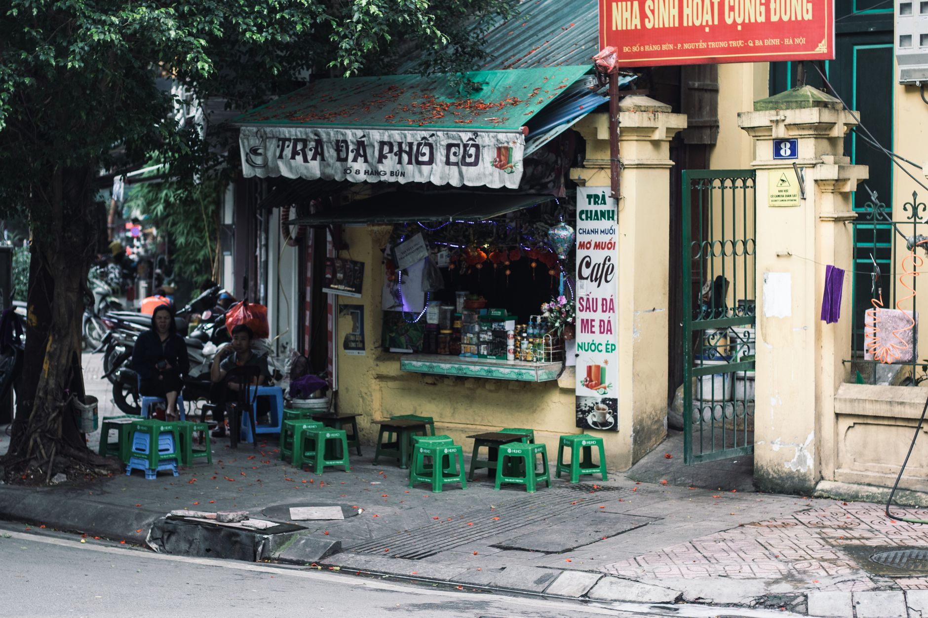 A bustling street corner cafe in Hanoi with local patrons and vivid colors.